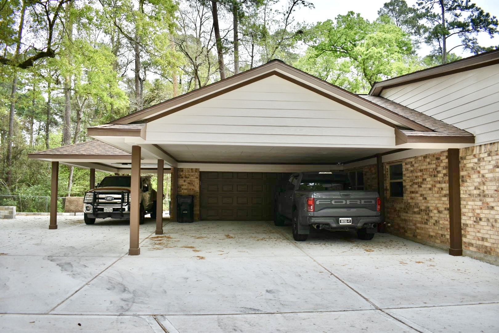 Covered carport addition attached to a brick home with two trucks parked underneath